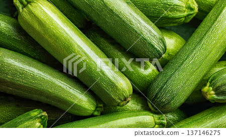 Fresh zucchinis in a neat arrangement, featuring their glossy green skin and varied sizes, create a visually delightful and appealing presentation 137146275