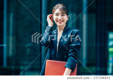 A young businesswoman in a suit using a smartphone in the office A young businesswoman in a suit using a smartphone in the office 137146851
