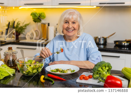 Senior old woman enjoying vegetable salad at home kitchen for healthy diet weight control nutrition Senior old woman enjoying vegetable salad at home kitchen for healthy diet weight control nutrition 137146888