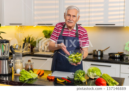 Senior old man teaching vegetable salad recipe in kitchen at home for healthy diet cooking tutorial Senior old man teaching vegetable salad recipe in kitchen at home for healthy diet cooking tutorial 137146889