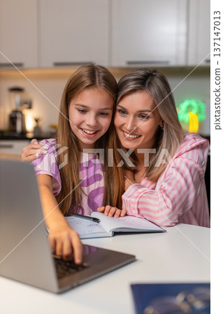 Mother and daughter finish online school homework on laptop click submit mother smiles closes laptop 137147013