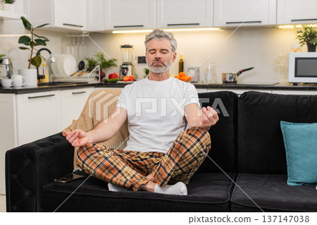 Middle-aged man sets meditation timer on smartphone sits straight breathes prepares for calm session Middle-aged man sets meditation timer on smartphone sits straight breathes prepares for calm session 137147038