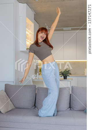 Young woman dances and jumps to loud music playful party mood carefree joy weekend vacation freedom 137147271
