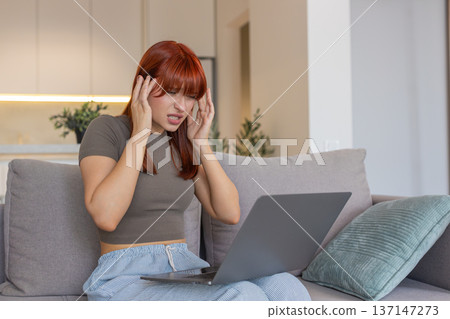 Young woman with laptop rubs temples headache pause closes eyes tired takes break for relief needed Young woman with laptop rubs temples headache pause closes eyes tired takes break for relief needed 137147273