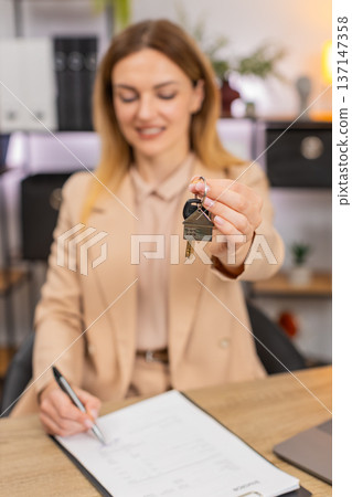 Businesswoman holds keys for new room signs contract paper smiles shows keychain starts new chapter Businesswoman holds keys for new room signs contract paper smiles shows keychain starts new chapter 137147358