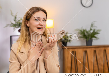 Businesswoman takes smartphone call with good news on speaker laughs thanks caller happy voice 137147369