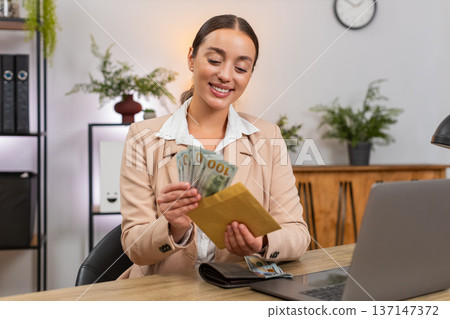 Young businesswoman counts dollar cash from wallet plans budget and puts part into reserve envelope 137147372