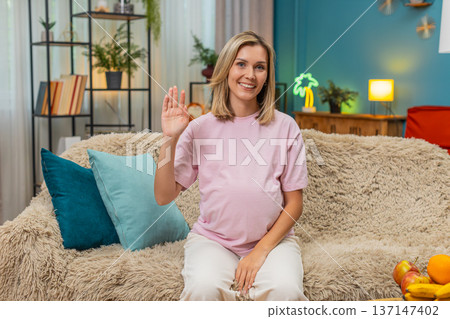 Pregnant woman waving greeting smiling hand raised friendly hello connection welcoming gesture open Pregnant woman waving greeting smiling hand raised friendly hello connection welcoming gesture open 137147402