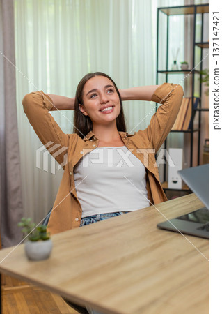 Young woman closing laptop leaning back with relief after finishing work smiling enjoying victory Young woman closing laptop leaning back with relief after finishing work smiling enjoying victory 137147421