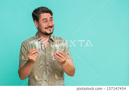 Man counting cash dollars money with satisfied smile expressing financial gain recent income savings Man counting cash dollars money with satisfied smile expressing financial gain recent income savings 137147454