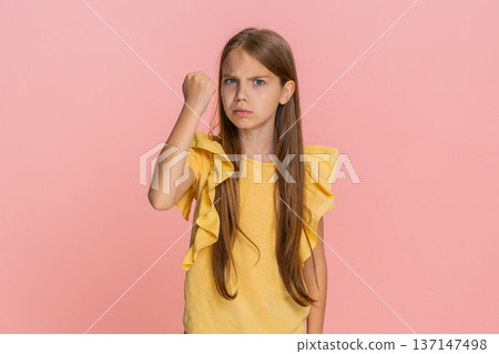 Child girl kid angrily shaking fist in funny way expressing dissatisfaction or playful mock threat 137147498