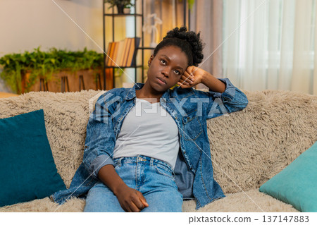 African American woman stressed on sofa thinking after bad day, financial failure or personal issues African American woman stressed on sofa thinking after bad day, financial failure or personal issues 137147883