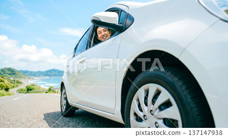 低角度拍攝的白色汽車、微笑的男子，以及令人驚嘆的海洋和藍天景色。 137147938
