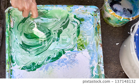 Painter craftsman mixes paints in a tray before work 137148132