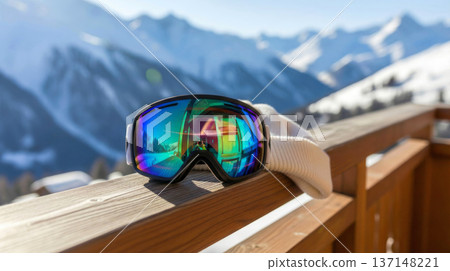 Ski goggles on wooden railing with mountain backdrop, winter sport gear 137148221