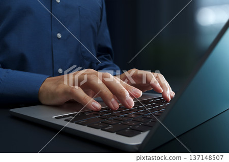 Business person using laptop at office desk. Close up of hands and keyboard. 137148507