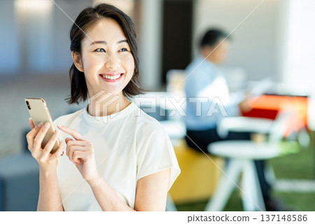 經營一部智能手機的女商人在辦公室 137148586