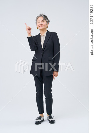 一位資深女商人擺出姿勢，食指向上豎起。 137149282