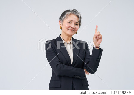 Senior businesswoman posing with index finger up 137149289