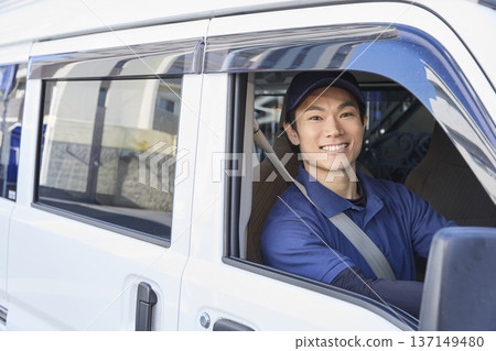 在送貨車駕駛座上,一位面帶微笑的司機 在送貨車駕駛座上,一位面帶微笑的司機 137149480