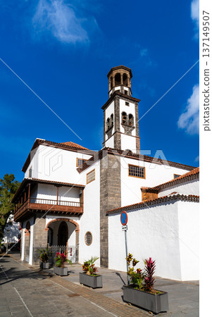 Scenic sunny view of the historic white facade, wooden balcony, and stone bell tower of Iglesia de la Concepcion in Santa Cruz de Tenerife, Canary Islands. 137149507