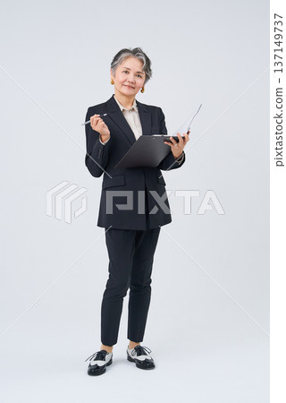 Senior businesswoman holding writing implements and files Senior businesswoman holding writing implements and files 137149737