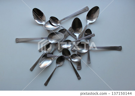 Heap Of Table Spoons And Dessert Spoons On White Plastic Cutting Board. Eating Utensils Concept Design  137150144