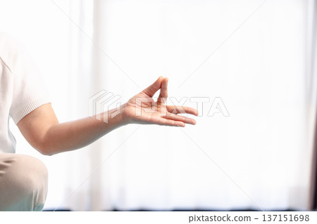 Close-up of hands in yoga meditation mudra during mindfulness practice, soft bright background with copy space. Calm wellness concept for relaxation, breathing, zen and mental health. 137151698