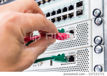 Hand of computer engineer connecting network cable in server cab Hand of computer engineer connecting network cable in server cab 137151772