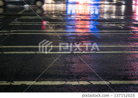 雨夜停車場:霓虹燈映照在瀝青路面和車轍上。 雨夜停車場:霓虹燈映照在瀝青路面和車轍上。 137152028