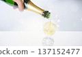 Hand pouring champagne into a glass and sparkling splashes 137152477