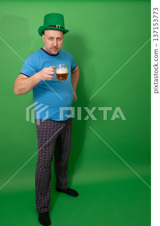 Man wearing green leprechaun hat holding frothy beer mug. St. Patricks Day Irish holiday celebration. Festive tradition fun and luck concept for seasonal greeting card. photography 137153773