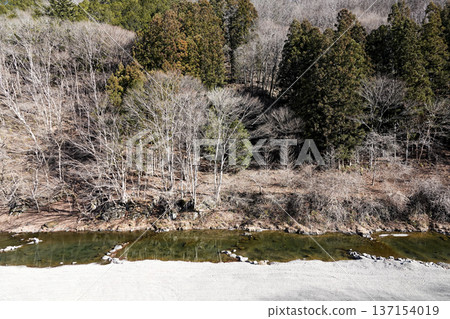 一條小河緩緩流淌在山谷中，對岸是冬天的樹木。 137154019
