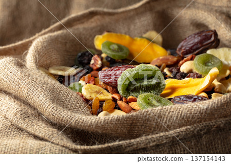 Dried tropical fruits and nuts in burlap bag. 137154143