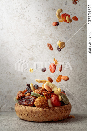 Mix of dried fruits and nuts in motion on a gray background. Mix of dried fruits and nuts in motion on a gray background. 137154293
