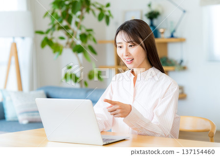 A woman who operates a personal computer in the living room A woman who operates a personal computer in the living room 137154460