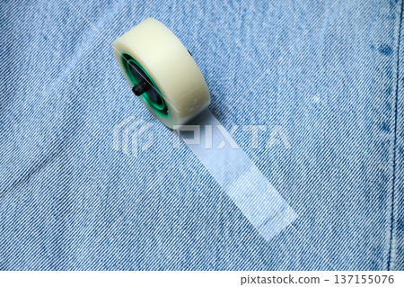 Roll of invisible tape on a denim jeans canvas 137155076