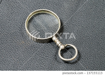 A small antique magnifying glass made of metal A small antique magnifying glass made of metal 137155113