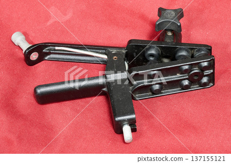 Sturdy photographic studio clamp against a red background Sturdy photographic studio clamp against a red background 137155121