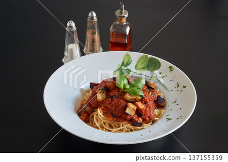 Plate of spaghetti melanzana pasta on a black wooden table 137155359