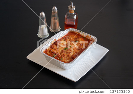 Plate of lasagne pasta on a black wooden table 137155360