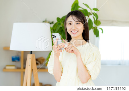 在房間裡操作智能手機的女人 在房間裡操作智能手機的女人 137155392