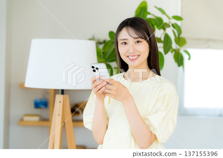 在房間裡操作智能手機的女人 137155396
