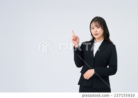 一位年輕的女商人擺姿勢,豎起食指。 一位年輕的女商人擺姿勢,豎起食指。 137155910