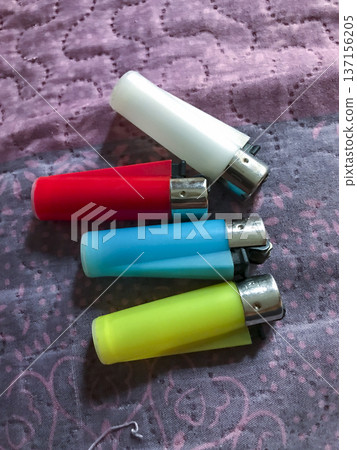 four colored lighters, blue,red,yellow and white on a cloth four colored lighters, blue,red,yellow and white on a cloth 137156205