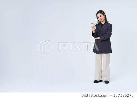 Young business woman operating a smartphone Young business woman operating a smartphone 137156273