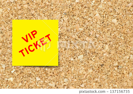 Yellow note paper with word VIP ticket on cork board background with copy space 137156735