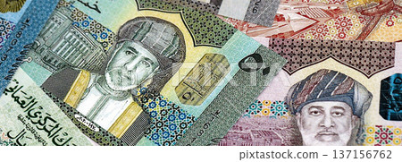 Omani rial paper banknotes pile on table. Oman OMR currency money bills in big amount. Concept of economics, taxation and banking in Oman 137156762
