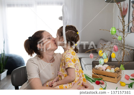 Mother and Daughter Share a Loving Kiss While Decorating for Easter 137157381
