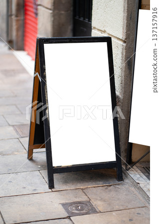 Blank sandwich board advertisement displaying white copy space on a city street, showcasing a rustic wooden frame and textured pavement for urban promotions Blank sandwich board advertisement displaying white copy space on a city street, showcasing a rustic wooden frame and textured pavement for urban promotions 137157916